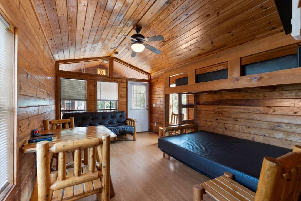 Open cabin room with sofa, bunks, and dining table.