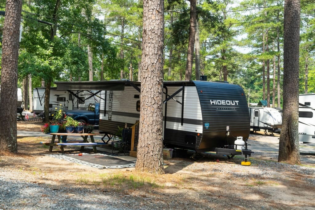 Hideout travel trailer parked at a shaded RV site.